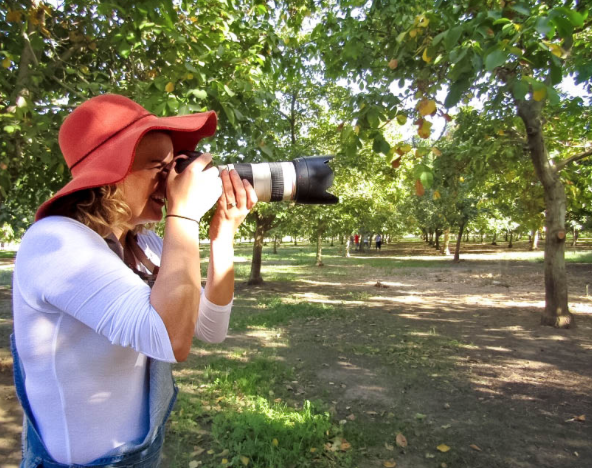 Christa Boynton holding camera to her eye in orchard